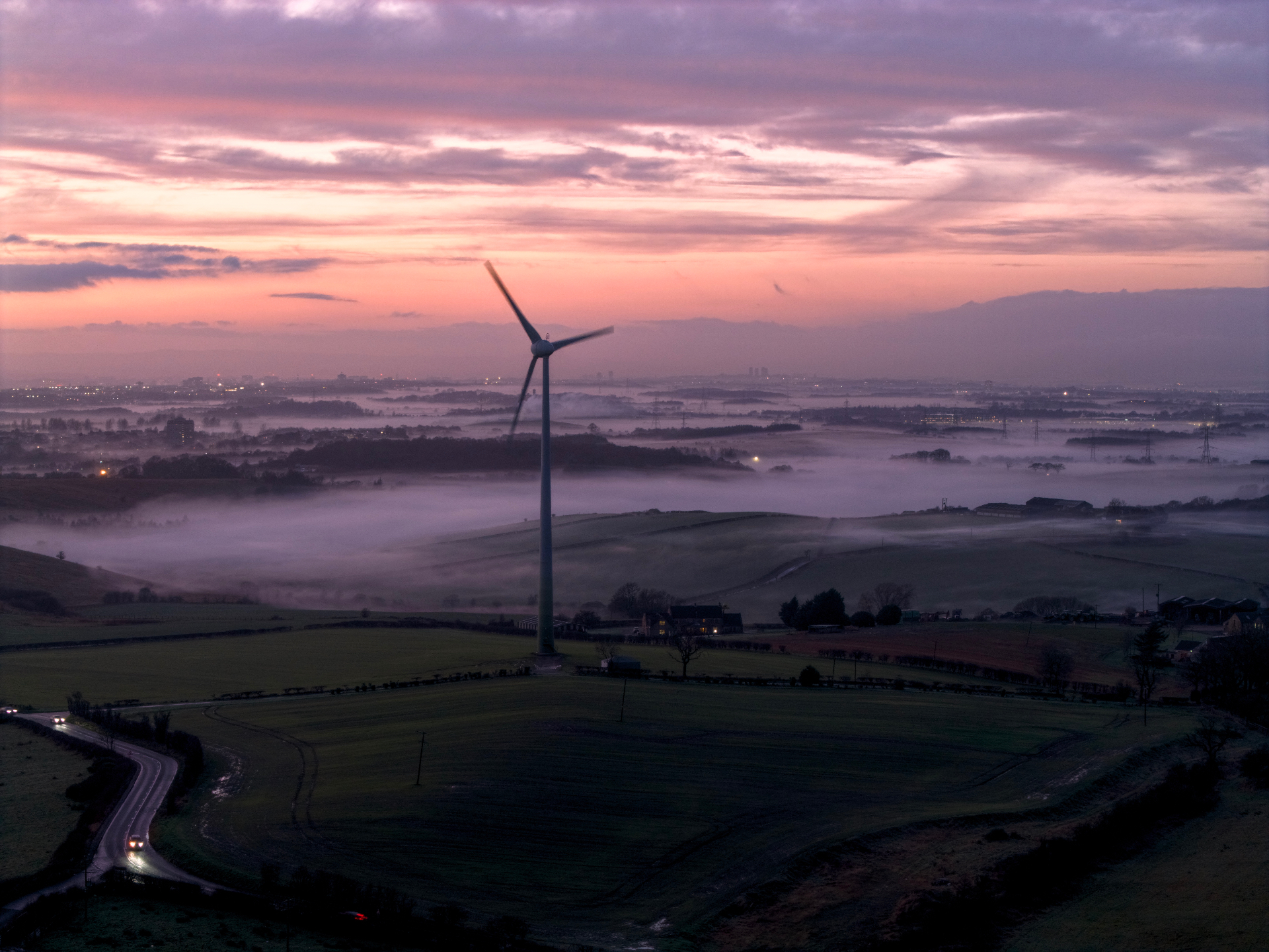 Wind turbine over misty Central Scotland at sunset